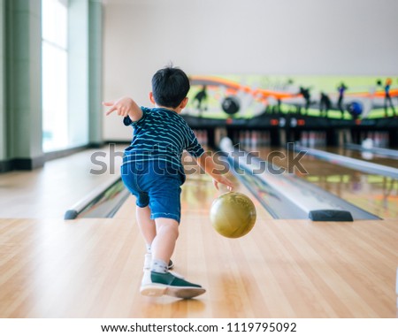  back view child throwing rolling bowling ball