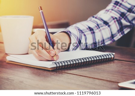 Business woman hand writing notebook on wood table.