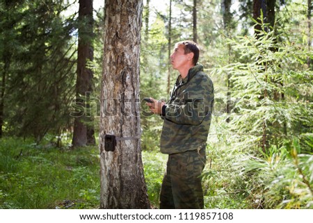 Foresters install photo traps on a tree for automatic photographing or video shooting of wildlife in the forest.