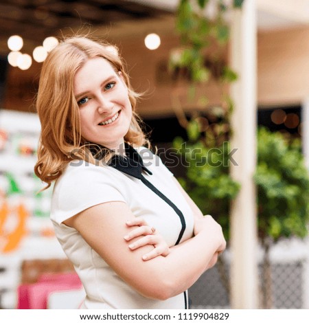 Portrait of blonde smiling woman posing in shopping mall.