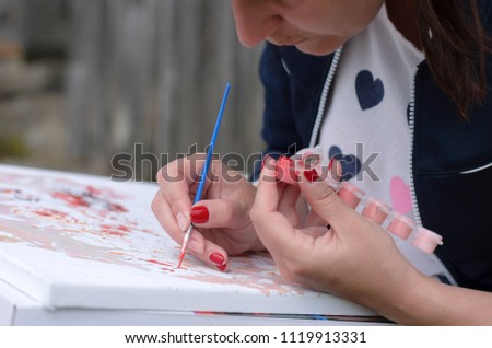 Girl enthusiastically draws a picture with a brush by numbers