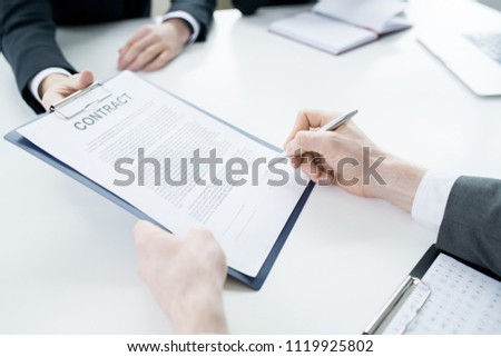 Close up of unrecognizable businessman signing contract during meeting with partners at table  in conference room, copy space
