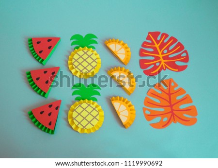 Fruits made from paper on a blue background. Pineapple, orange, lemon, watermelon, kiwi, apple. View from above. Children's creativity. Tropical party of Hawaii.