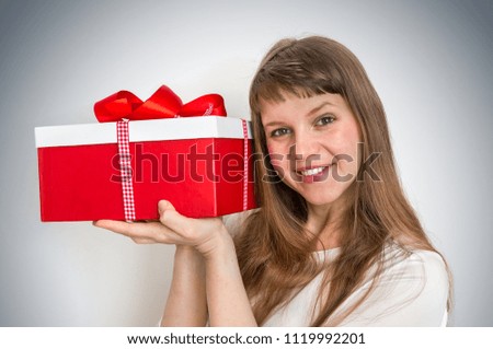 Pretty smiling woman with red gift box over gray background