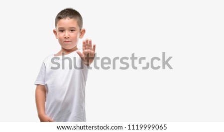 Dark haired little child with open hand doing stop sign with serious and confident expression, defense gesture