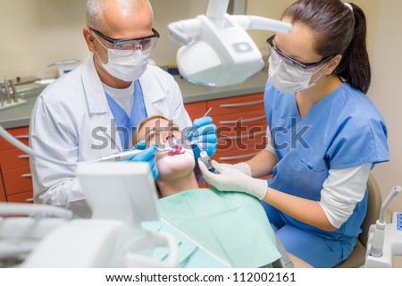 Professional dentist and nurse doing operation on female patient Royalty-Free Stock Photo #112002161