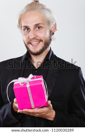 People celebrating xmas, love and happiness concept - cool young man holding present pink gift box in hand