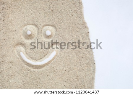 Smily face drawn on sand in white isolated background.