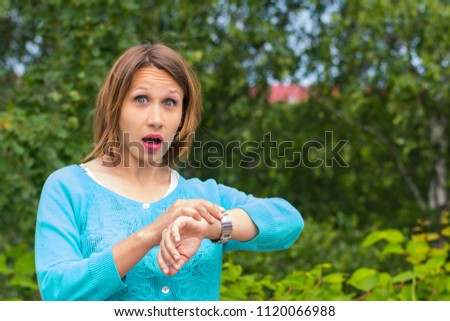 young woman looks at the clock on his hand in the Park