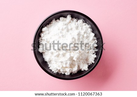 Bowl of powder sugar on pink background, top view