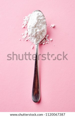 Spoon with powder sugar isolated on pink background, top view