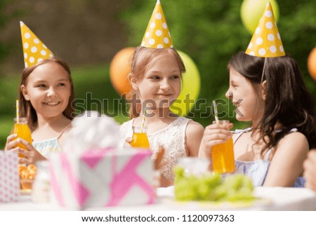 holidays, childhood and celebration concept - happy girls drinking juice on birthday party at summer garden