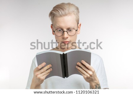 Handsome blond srudent man in spectacles reading grey book, preparing to exams in colledge, isolated over white background with copy space