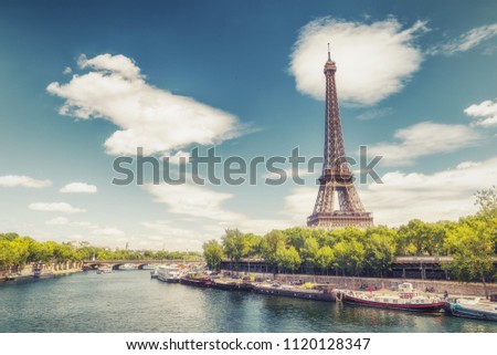 The Eiffel Tower in Paris, France, on a summer day with the Seine river and dramatic clouds.  Colourful travel background. 