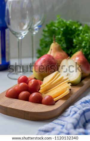 Snack (pears, cheese, cherry tomatoes) and two glasses for wine