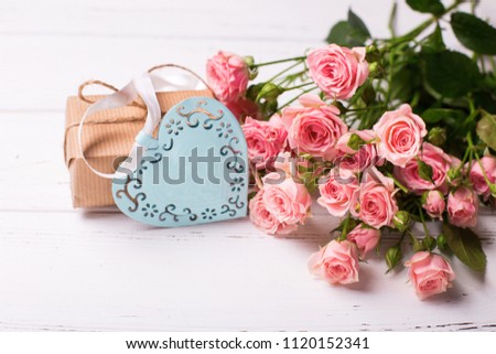 Pink roses flowers, decorative heart and  box with present on white wooden background. Floral still life.  Selective focus. Place for text.