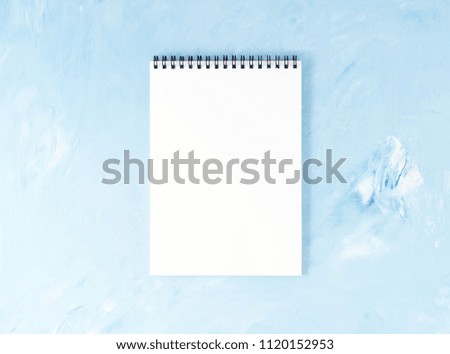 Top view of modern bright blue office desktop with notepad. Mock up, empty space