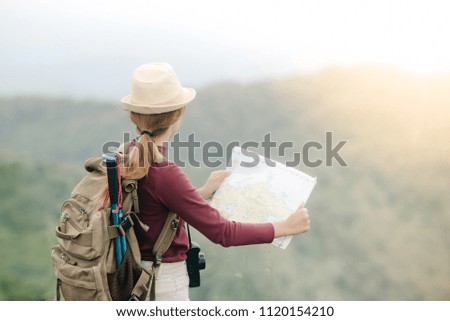 Hipster asian women with backpack enjoying large veiw of mountain and sky on peak of mountain spot. Tourist traveler have accessories such as hat , backpack , camera, and map