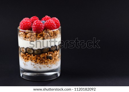 Healthy blueberry and raspberry parfait in a glass on a black background. Two portions. Space for text or design.