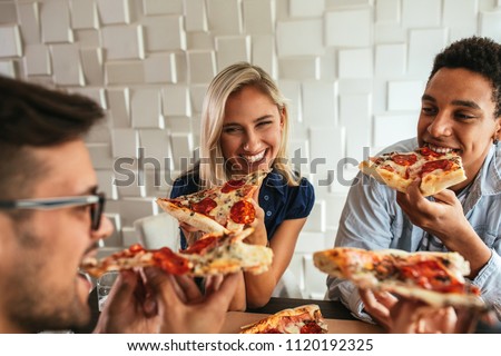Shot of a group of friends eating pizza in a bar