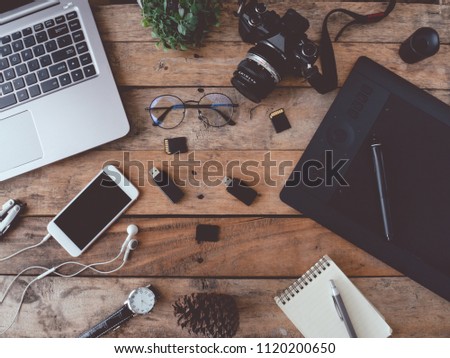 top view of graphic design and photographer concept with digital camera, memory card, smartphone, graphic tablet, and laptop on wooden background.