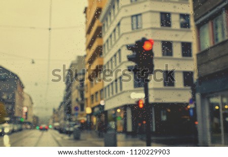 Rain. Rainy evening in the city. Drive. Poor weather conditions. Red traffic light. Overcast. Shower. Bad visibility on roads. Perspective. Blurred avenue scene. Drops of rain. Blur urban background