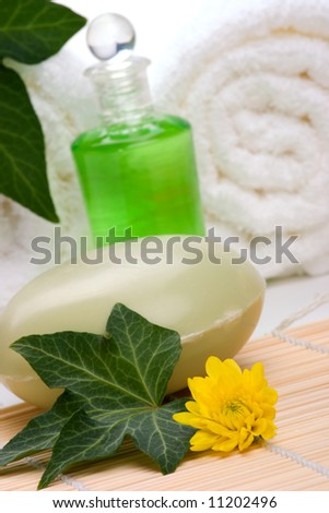 Spa set - Chrysanthemums flowers, body oils, organic soap on bamboo mat and towels with ivy leaves over white background best suited for relaxing and health commercials