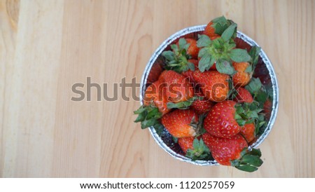  Fresh ripe strawberry in a bowl on wooden background.                              