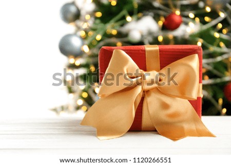 Beautiful gift box and blurred Christmas tree on background