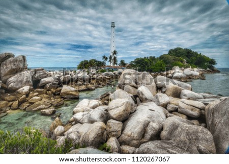 Lengkuas Island with its beach full of granite rocks. Lighthouse as the background of the picture.
