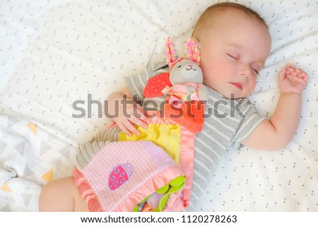 Adorable baby sleeping in bed with bright rabbit toy. Nursery for children. Understanding your baby's sleep
