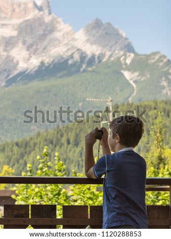 Young Boy Taking Photo with Camera in Mountain in Summer Time.