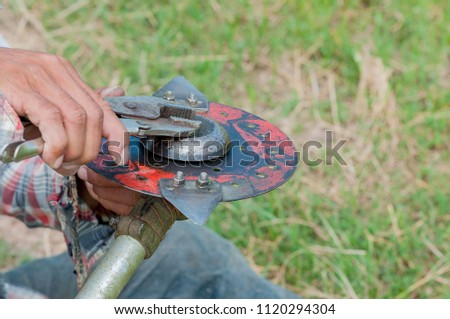 Farmer are changing the mower blade. Picture is selective focus and close up style. Background is green grass.