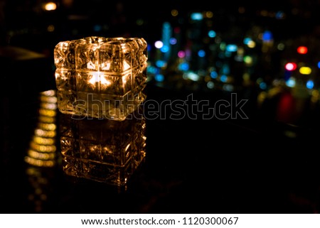Burning candle in glass cup with abstract background