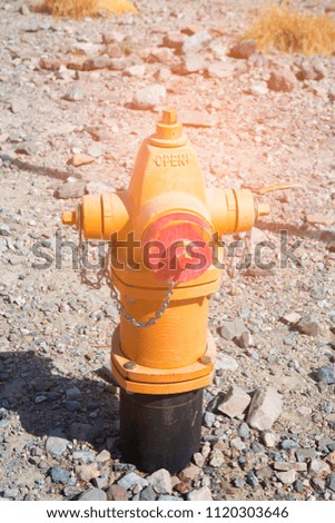orange fire hydrant on dirt with rock floor