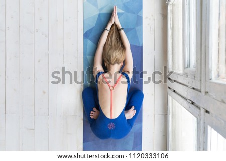 Top view of beautiful young fitness woman in blue jumpsuit working out on white wooden floor at home, doing yoga exercise, full length