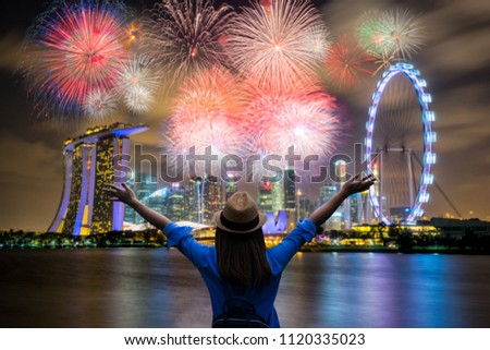 Young woman traveler celebrate and looking view of Singapore city landmark financial district at twilight sunset scene with multicolor firework celebration. Singapore city in national day celebration. Royalty-Free Stock Photo #1120335023