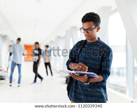 A student at the University with a book in his hands. student from India. The photo illustrates student life, education at University or College.