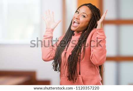 Portrait of a young black woman wearing braids laughing and having fun, being relaxed and cheerful, feels confident and successful