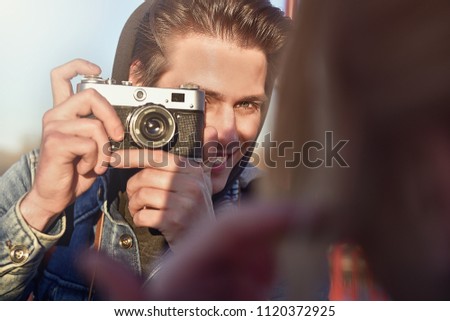 Stylish man photographing a woman on retro camera in the street.
