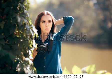 Female Paparazzi with Camera Hiding in the Bushes. Woman photographer in nature taking pictures 
