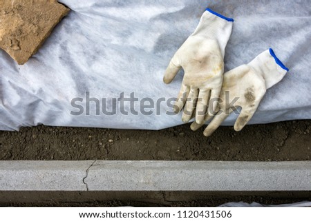 Setting edge restraints buy putting border curb stones in earth-moist concrete with two gloves