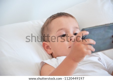 baby boy before going to bed and watching cartoons in the smartphone