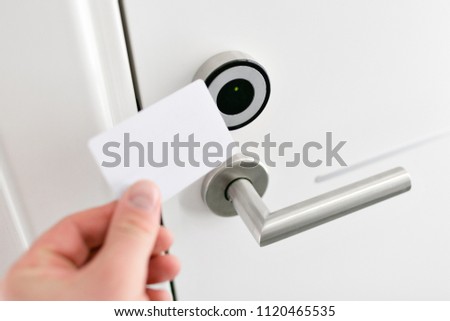 Hotel door - Young man holding a keycard in front of the electronic sensor of a room door. Concept travel or business trip Royalty-Free Stock Photo #1120465535