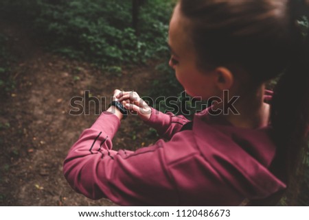 Yong woman athlete adjusts the smart watch before her run outdoors. Cropped top view of a sporty girl setting fitness bracelet on training. Smart watch health, heart rate and calories burn monitoring Royalty-Free Stock Photo #1120486673