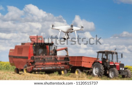 Drone flying in front of tractor and combine harvester in field in early summer. Technology innovation in agriculture