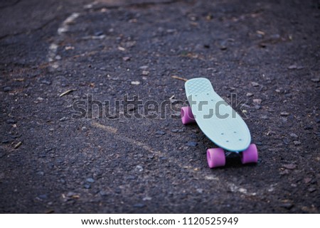 Blue penny board with pink wheels stands on the track.