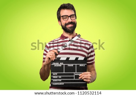 Happy Man with glasses holding a clapperboard on colorful background