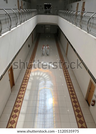 Saudi men wearing the traditional clothes are walking in the corridor