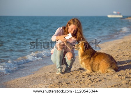 happy fun weekend by the sea - smiling girl with a dog do selfie on smartphone on the beach
